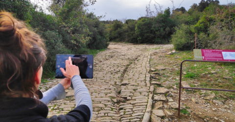 Photo d'une personne tenant une tablette pour illustrer la visite du site archéologique d'Ambrussum grâce à l'application 3D.