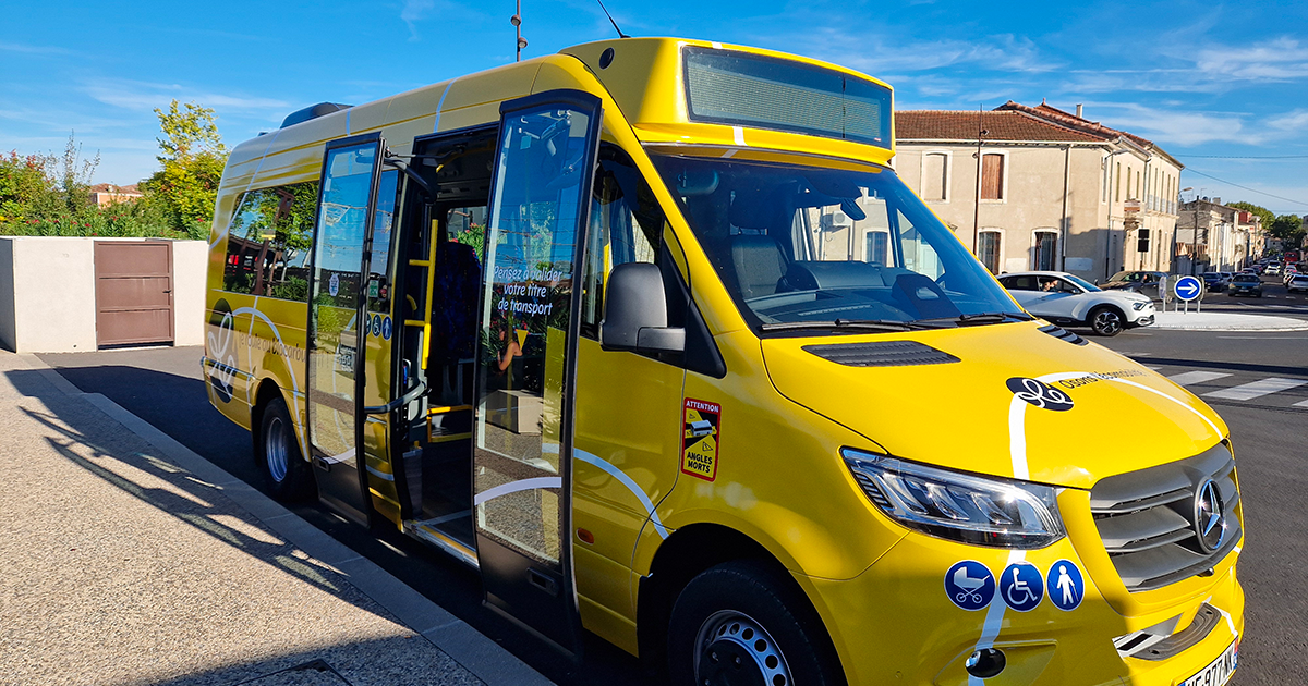 Photo d'un minibus jaune, réseau de tranport de Lunel Agglo, avec l'inscription "Olé" blanche dans un rond noir, avec des volutes blanche.