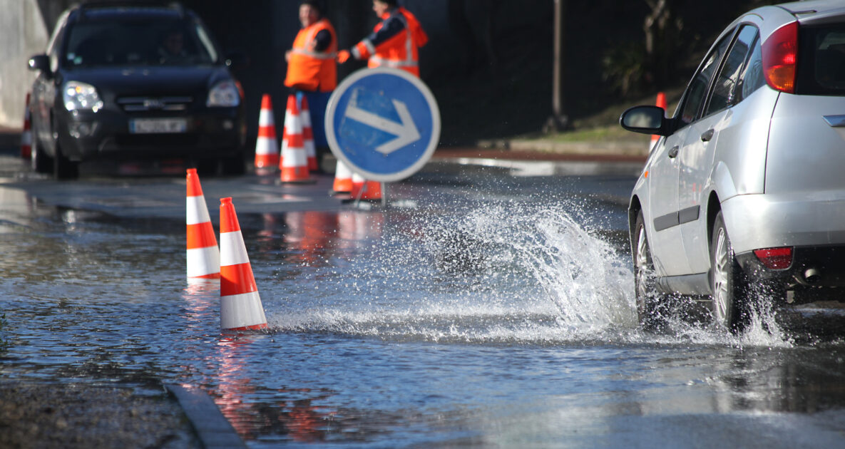 Une voiture passe dans une flaque d'eau importante liée à une inondation.