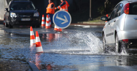 Une voiture passe dans une flaque d'eau importante liée à une inondation.