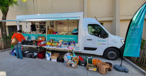 Photo d'un camion étale proposant d'apporter et de récupérer gratuitement des objet de seconde main. Devant une personne regarde les objets proposés sur le comptoir.