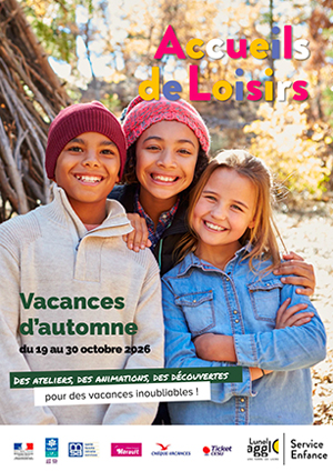 Photo de trois enfants souriants, regroupés dans la nature. Le garçon et la fille sur la gauche portent un bonnet, la fille sur la droite porte une chemise en jean. Ils se trouvent devant un tas de bois et en arrière-plan, on voit des arbres dont les feuilles ont pris les couleurs de l'automne. Cette photo illustre la couverture du programme des animations dans les accueils de loisirs de Lunel Agglo, du 19 au 30 octobre 2026.